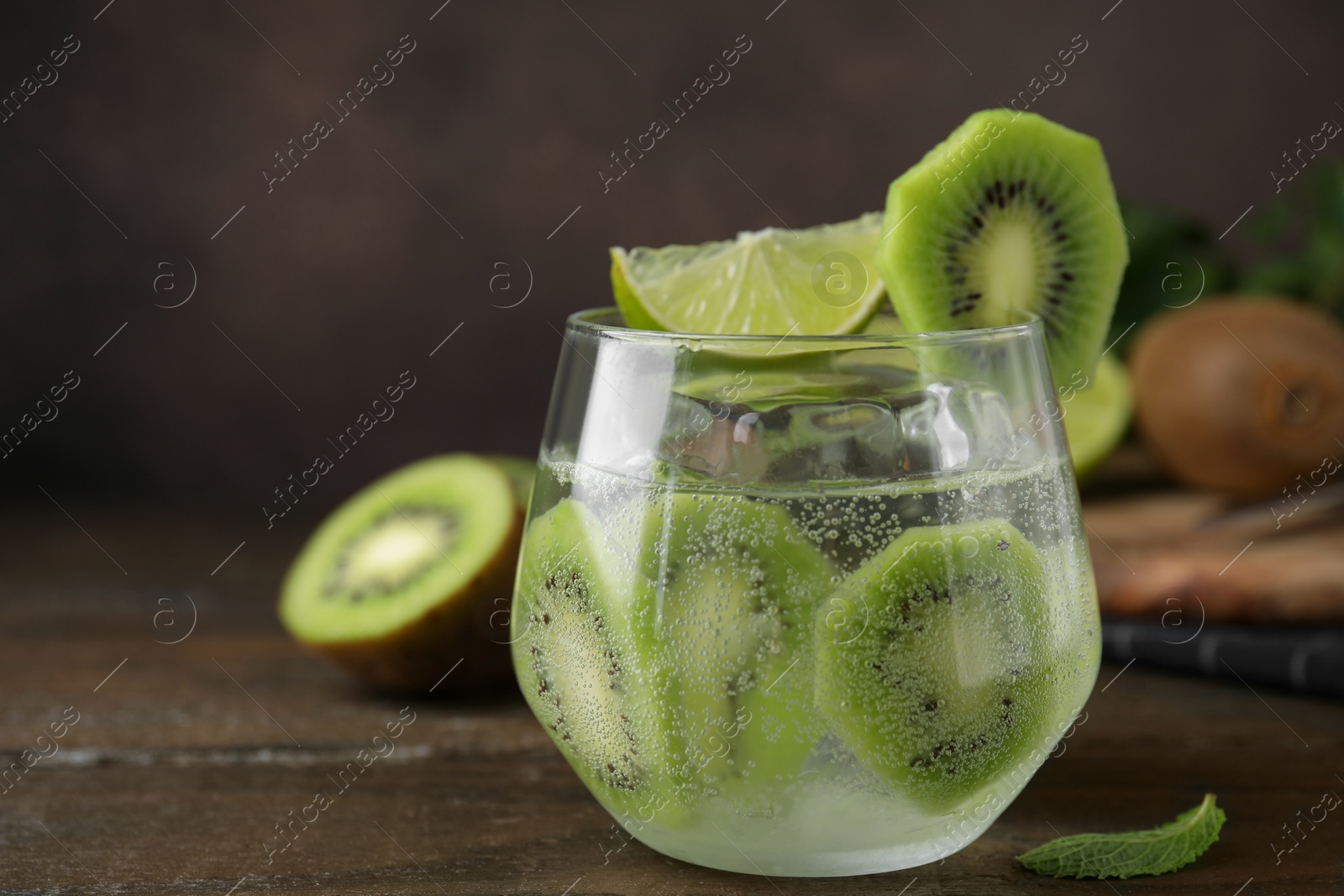 Photo of Glass of refreshing drink with cut kiwi on wooden table, closeup. Space for text