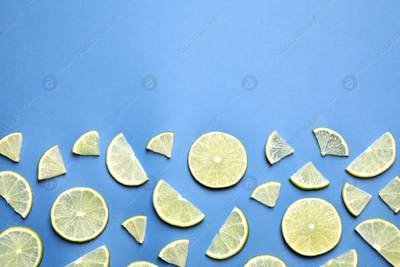 Photo of Juicy fresh lime slices on blue background, flat lay. Space for text