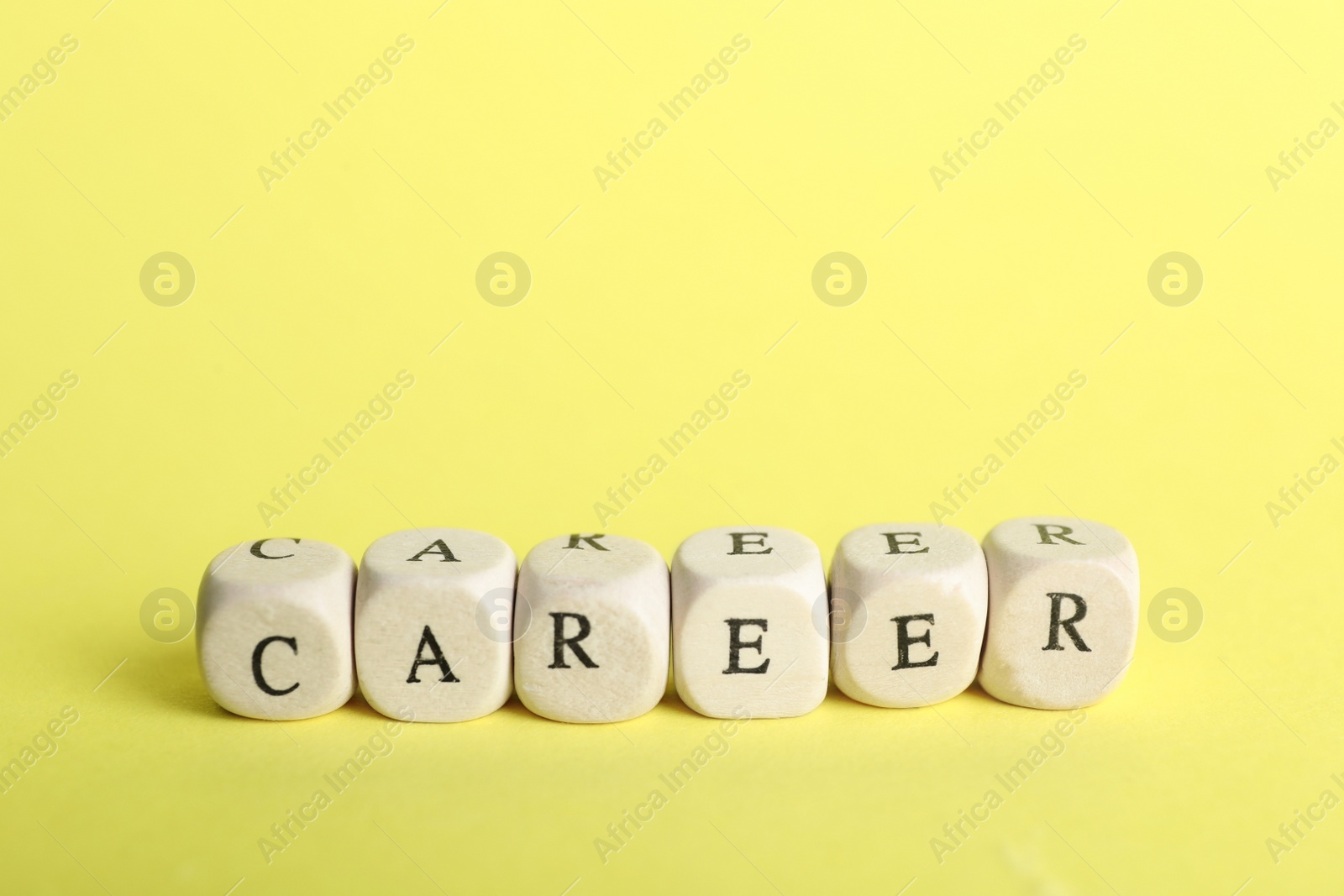 Photo of Stone cubes with word CAREER on yellow background. Space for text