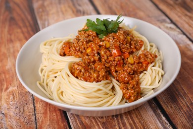 Tasty dish with fried minced meat, spaghetti, carrot and corn on wooden table, closeup