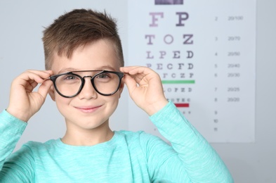 Little boy with glasses visiting children's doctor in clinic, space for text. Eye examination