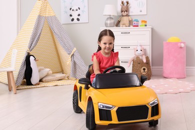 Adorable child driving toy car in room at home