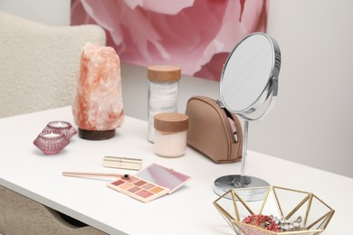 Dressing table with mirror, cosmetic products, jewelry and burning candles in makeup room