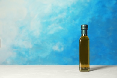 Bottle of oil on table against color background. Space for text