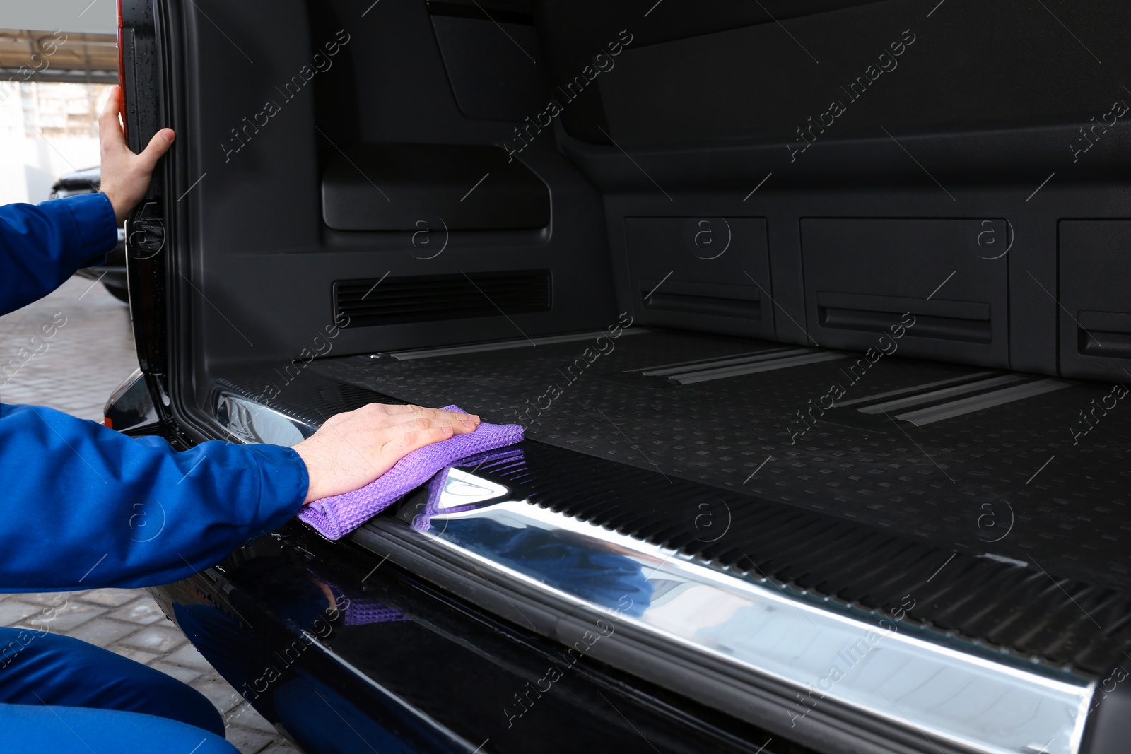 Photo of Worker wiping automobile trunk with rag at car wash, closeup