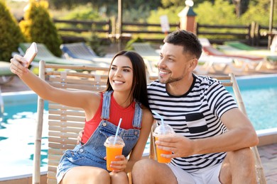 Image of Happy couple taking selfie in deck chairs outdoors