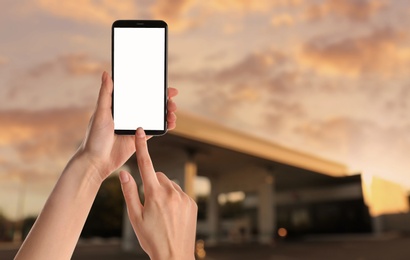 Image of Woman paying for refueling via smartphone at gas station, closeup. Device with empty screen