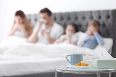 Photo of Table with cold remedies and blurred sick family on background