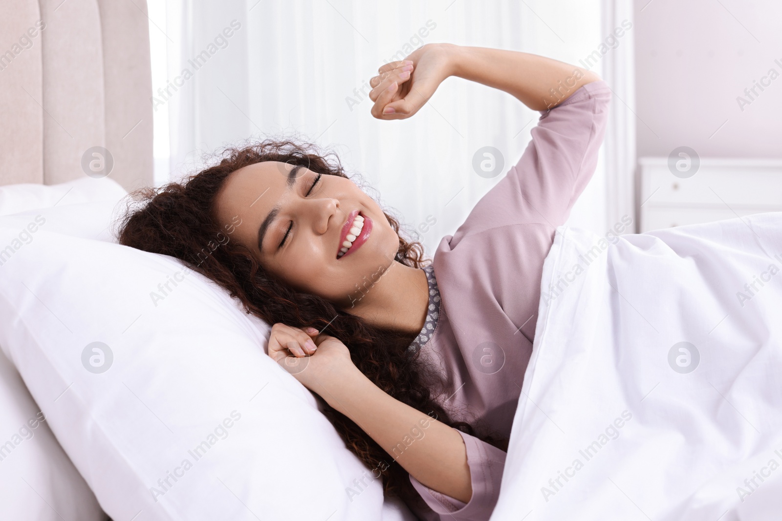 Photo of Happy African American woman awakening in bed at home