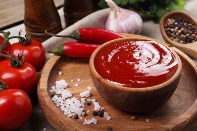 Photo of Delicious ketchup in bowl, products and spices on table, closeup. Tomato sauce