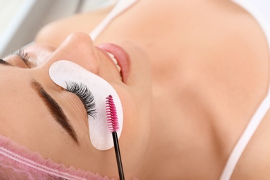 Young woman undergoing eyelash extensions procedure, closeup