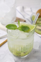 Photo of Glass of refreshing drink with kiwi, lime and mint on white table, closeup