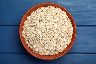 Photo of Bowl of oatmeal on blue wooden table, top view