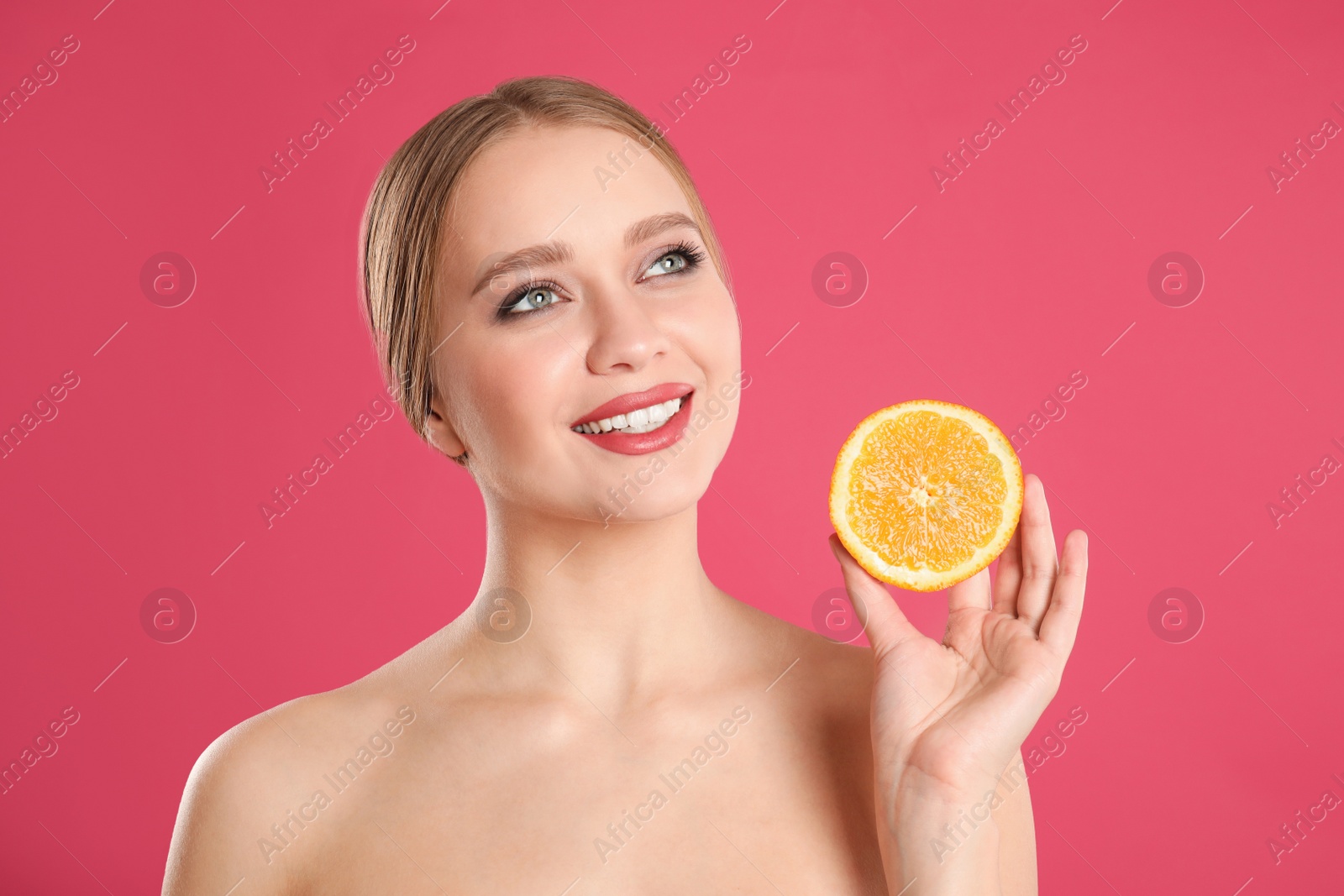 Photo of Young woman with cut orange on pink background. Vitamin rich food