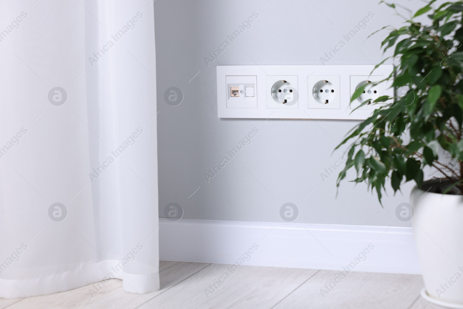Photo of Electric power sockets on light grey wall indoors, space for text