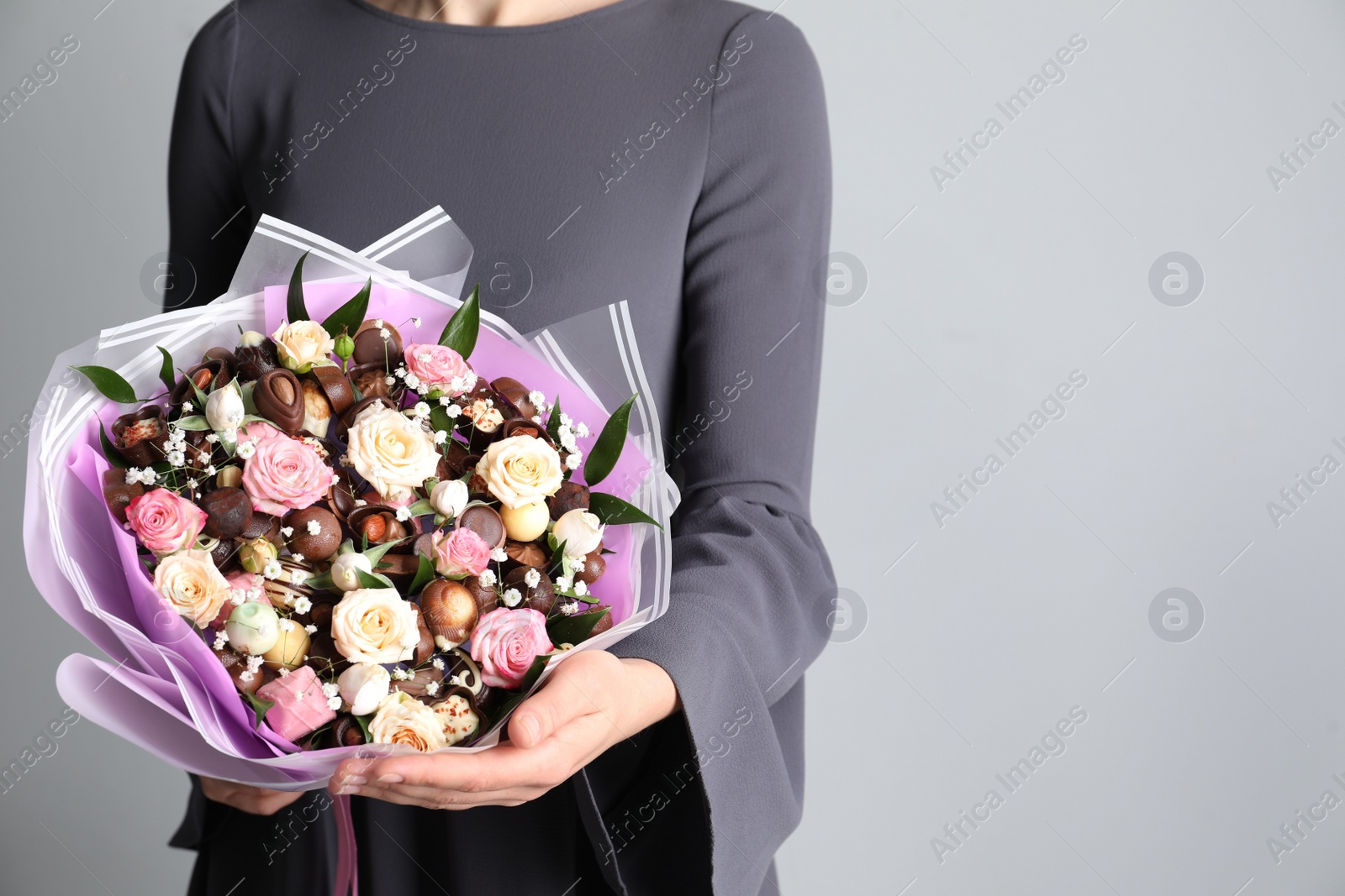 Photo of Woman with beautiful food bouquet on light grey background, closeup. Space for text
