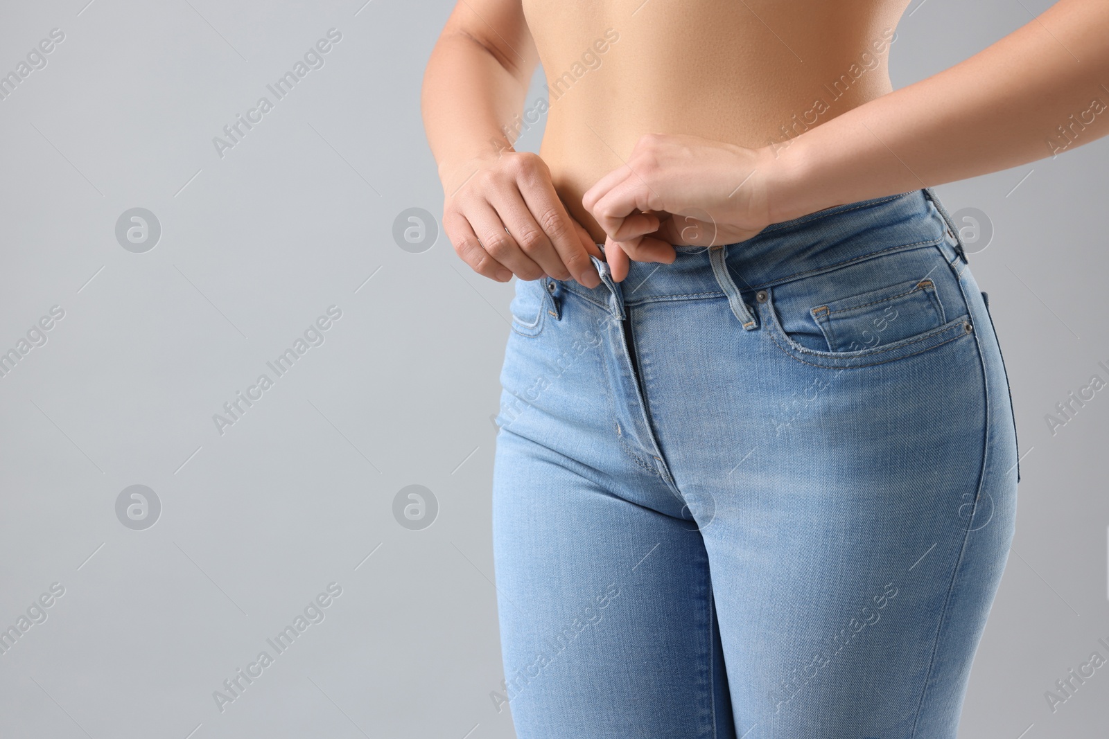 Photo of Woman wearing stylish jeans on light gray background, closeup. Space for text