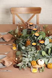 Autumn table setting with eucalyptus branches and pumpkins indoors
