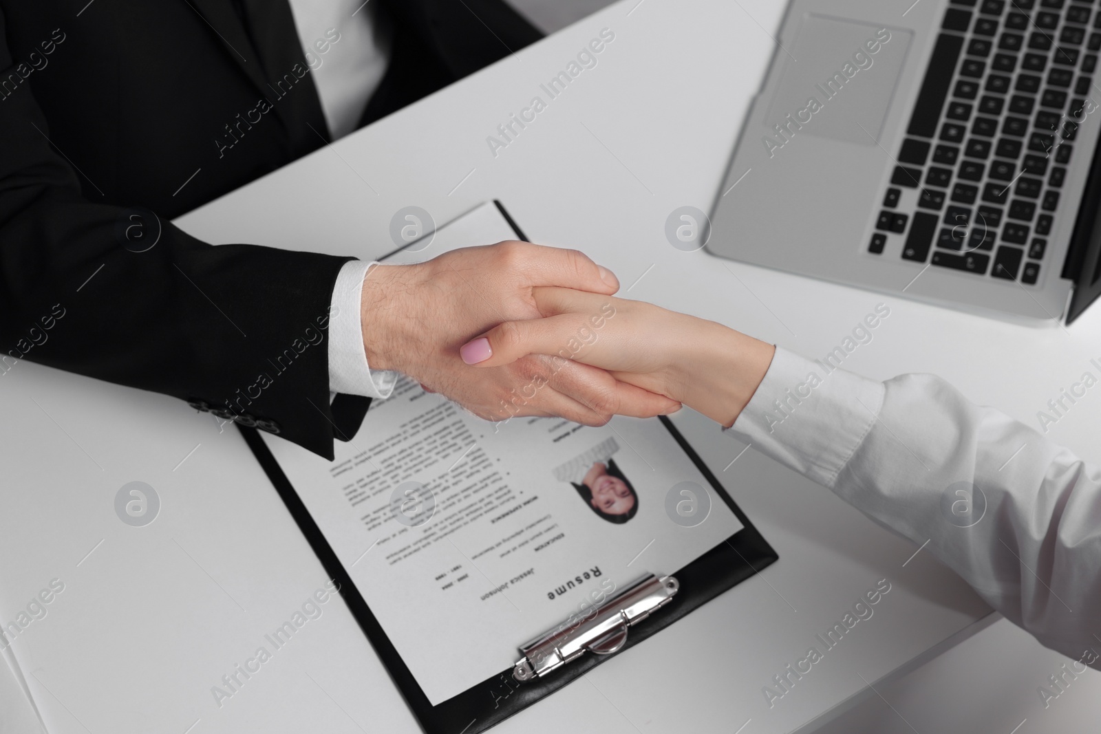 Photo of Human resources manager shaking hands with applicant during job interview in office, above view