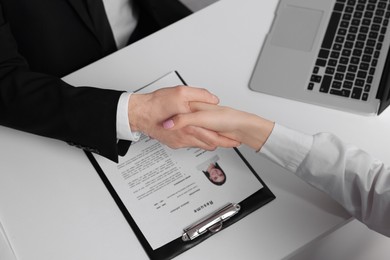 Photo of Human resources manager shaking hands with applicant during job interview in office, above view