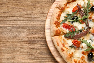 Tasty pizza with anchovies, arugula and olives on wooden table, top view. Space for text