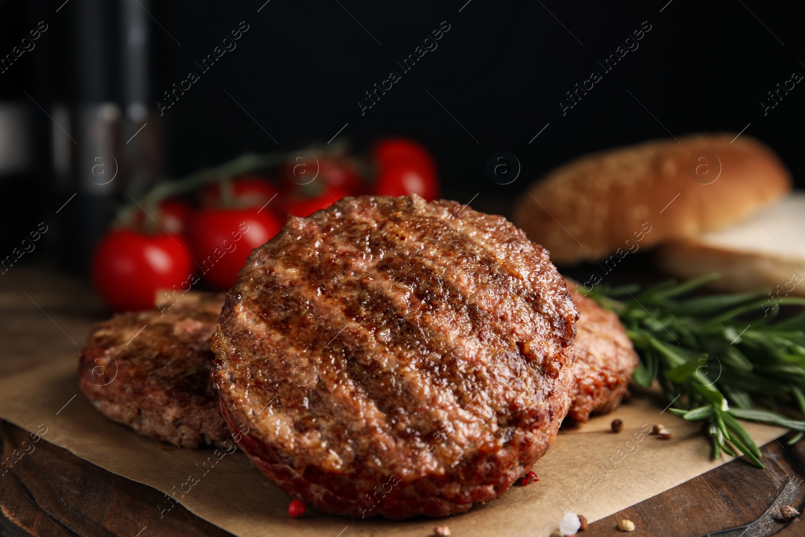 Photo of Tasty grilled hamburger patties with seasonings on wooden table, closeup