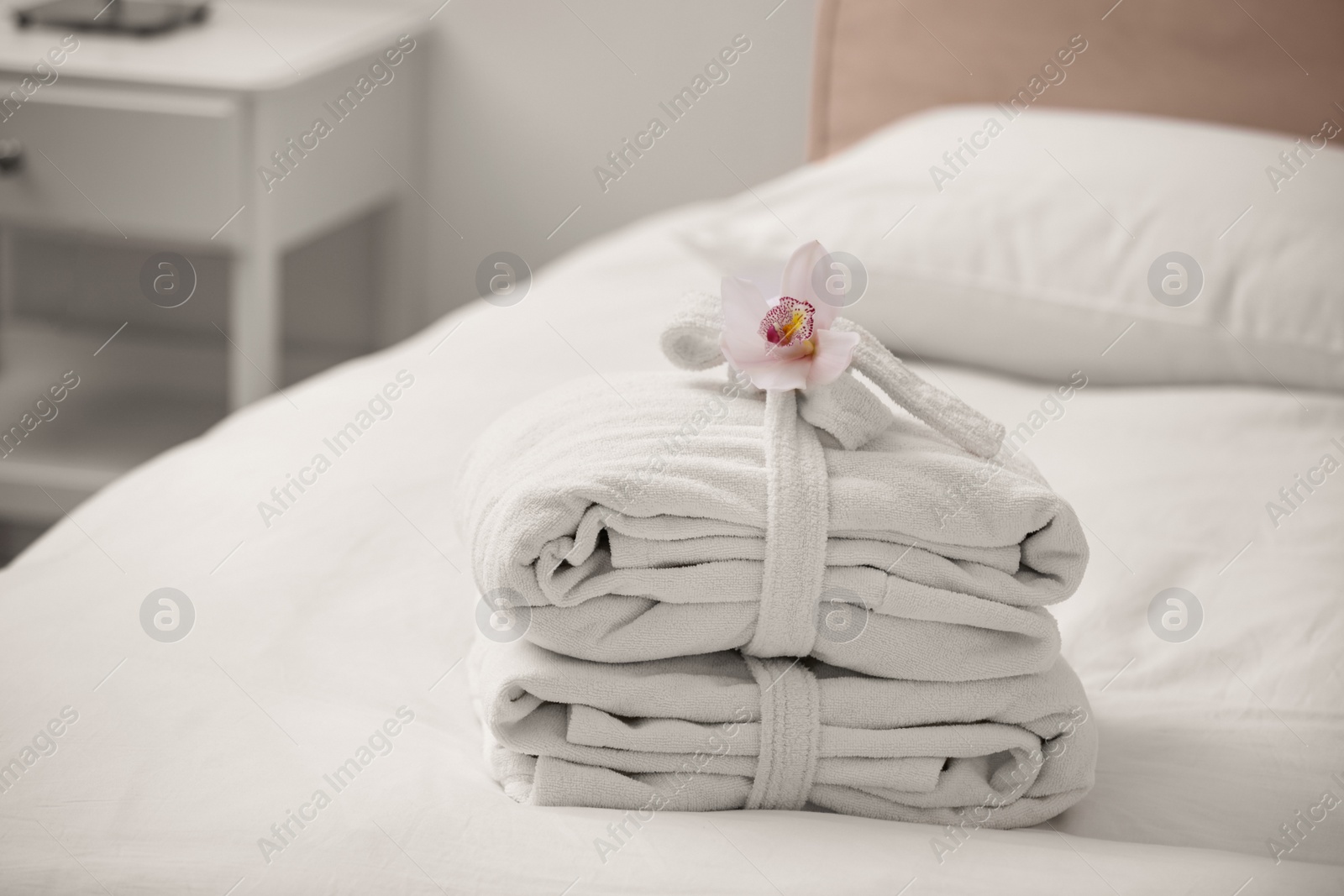 Photo of Clean folded bathrobes on bed in room