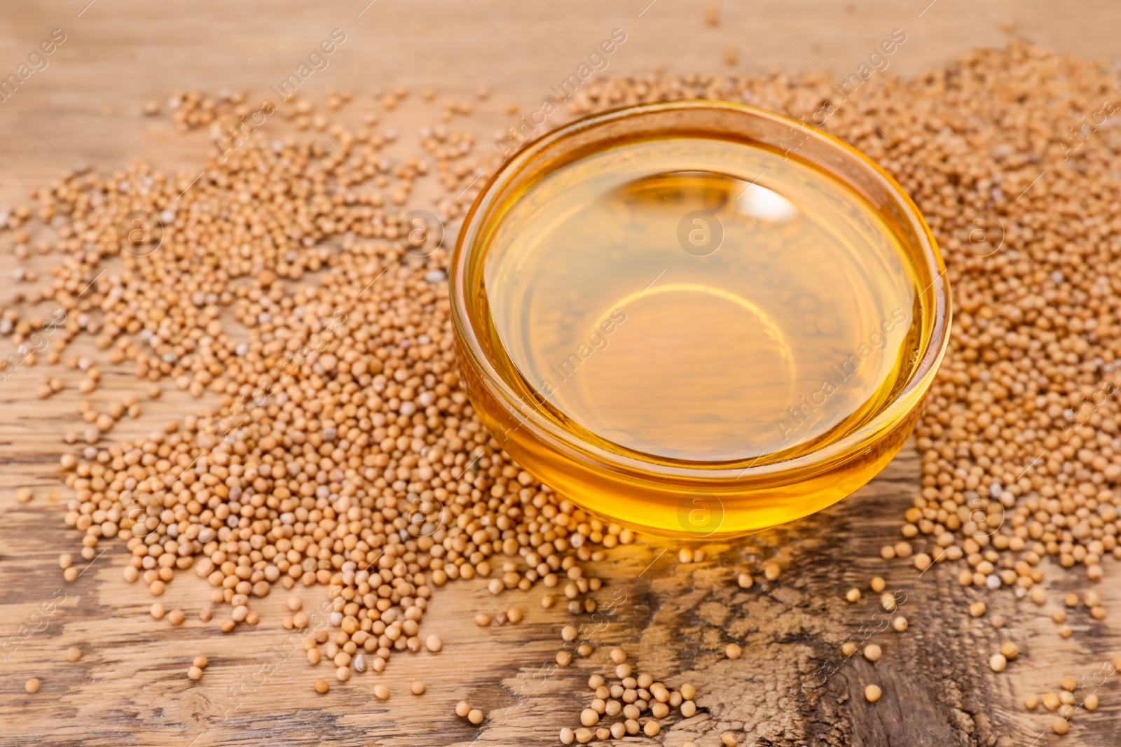 Bowl of natural oil and mustard seeds on wooden table. Space for text Photo of Bowl of natural oil and mustard seeds on wooden table. Space for text