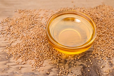 Photo of Bowl of natural oil and mustard seeds on wooden table. Space for text