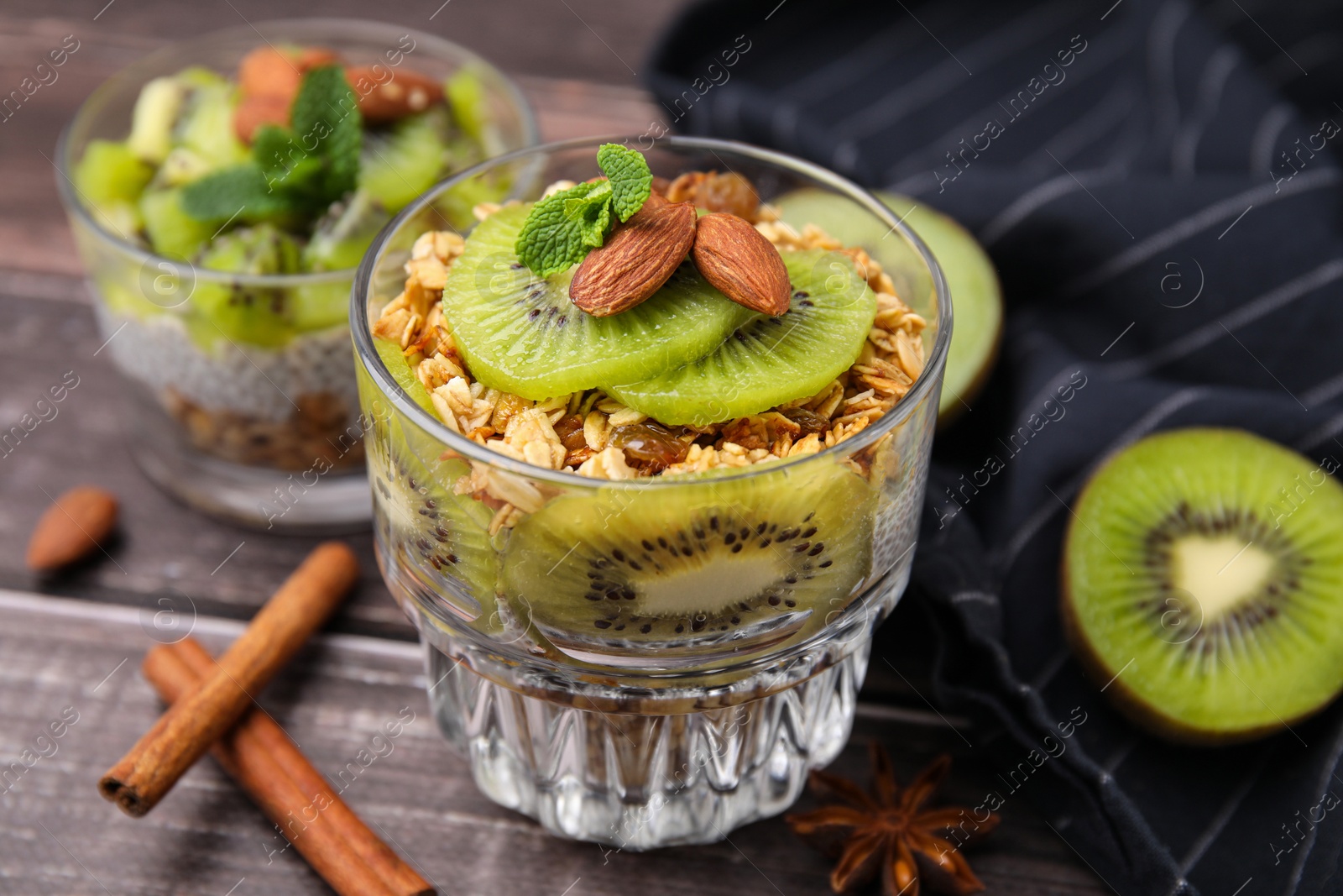 Photo of Delicious dessert with kiwi muesli and almonds on wooden table, closeup