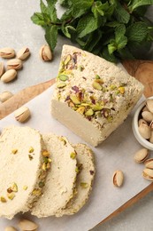 Photo of Tasty halva with pistachios and mint on light grey table, top view