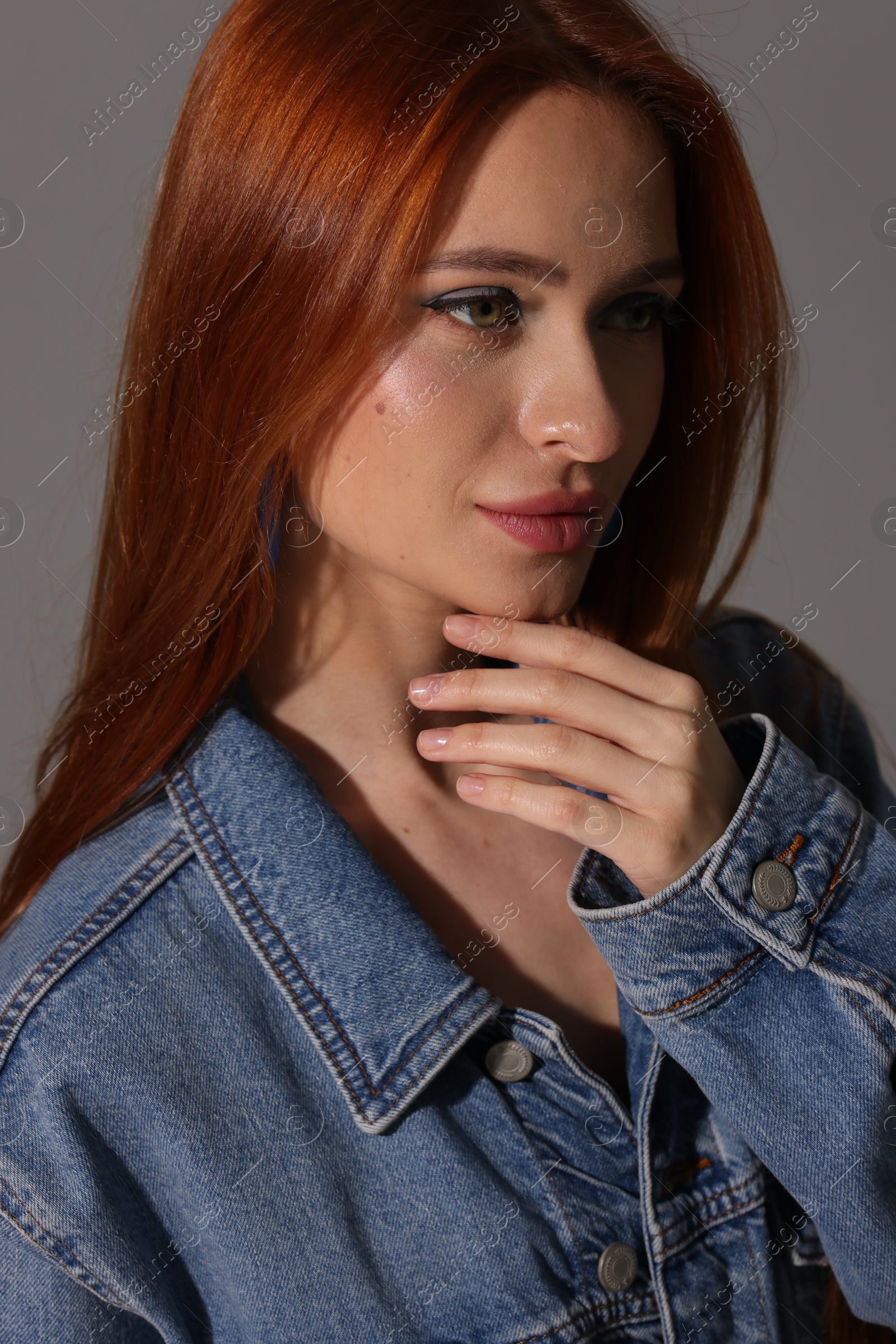 Photo of Beautiful young woman in denim jacket on gray background