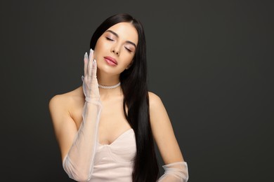 Photo of Portrait of beautiful young woman in evening gloves on black background