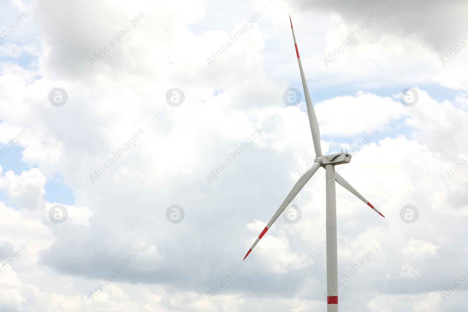 Photo of Modern wind turbine against cloudy sky, closeup. Alternative energy source