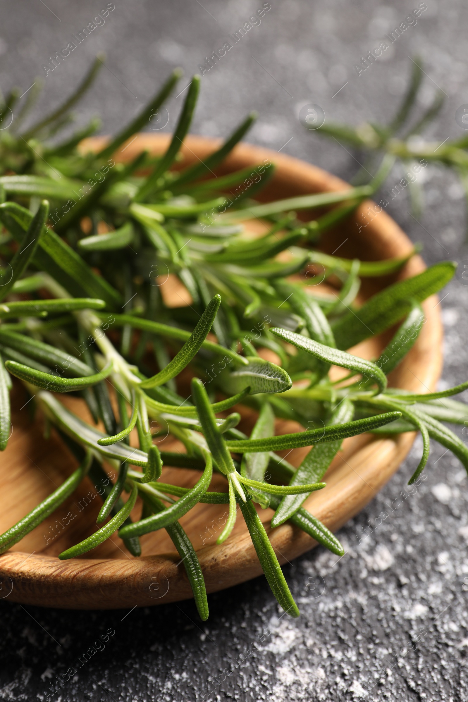 Photo of Fresh rosemary on grey textured table, closeup