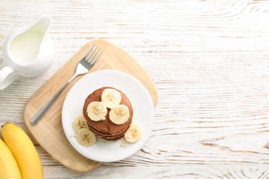 Photo of Plate of banana pancakes served on white wooden table, flat lay. Space for text