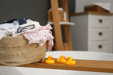 Laundry basket with baby clothes on tub tray in bathroom, closeup. Space for text