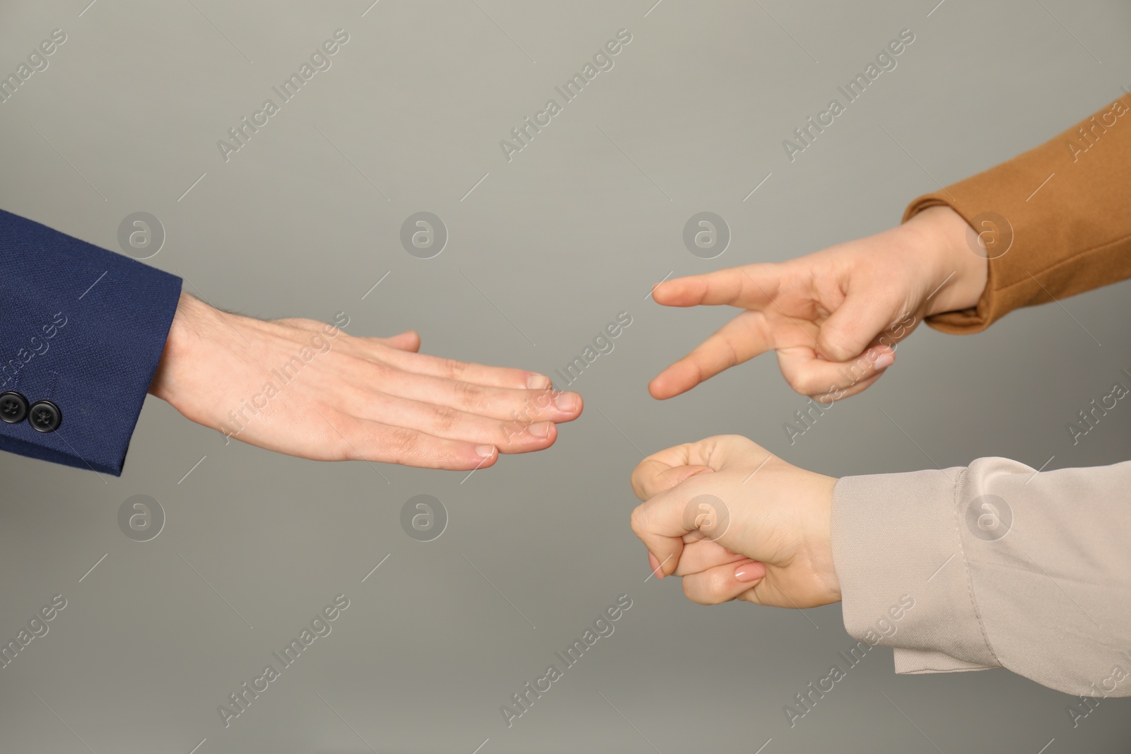 Photo of People playing rock, paper and scissors on grey background, closeup
