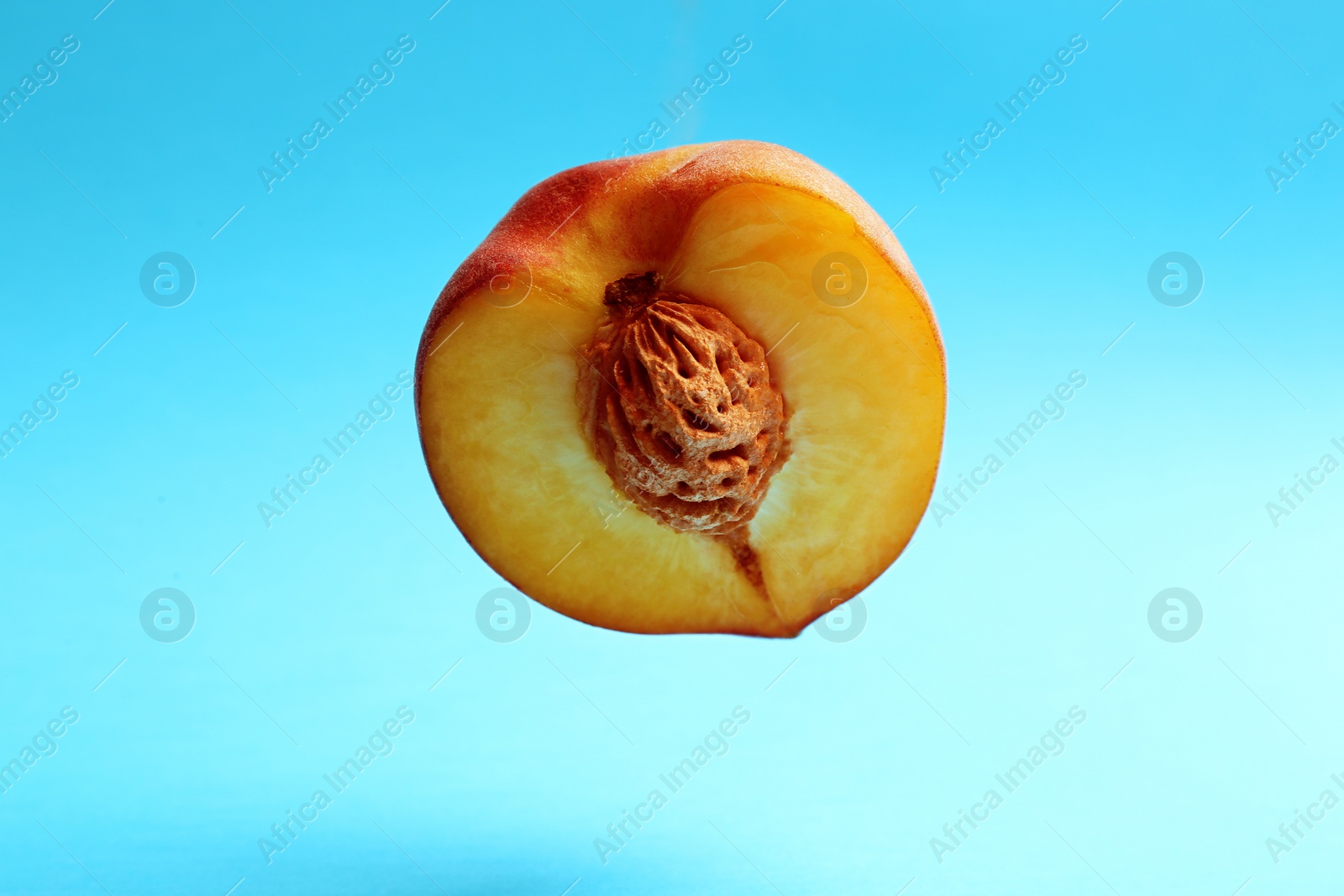 Photo of Half of fresh juicy peach on blue background