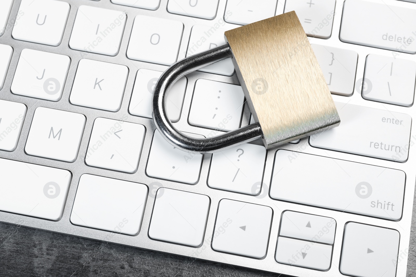 Photo of Cyber security. Metal padlock and keyboard on grey table, above view