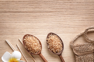 Photo of Flat lay composition with brown sea salt on wooden background, space for text. Spa treatment