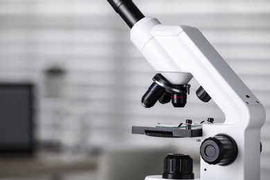 Photo of Modern medical microscope on blurred background, closeup with space for text. Laboratory equipment