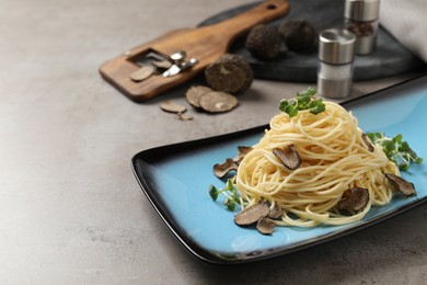 Photo of Delicious pasta with truffle slices and microgreens served on light grey table, space for text