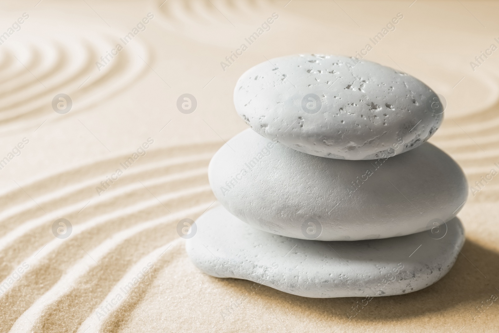 Photo of Stacked zen garden stones on sand with pattern, space for text. Meditation and harmony