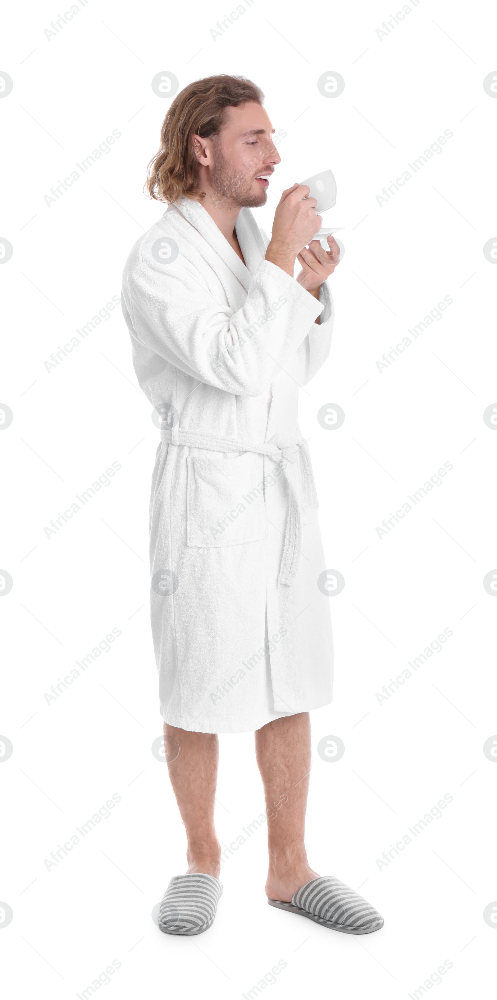 Photo of Young man in bathrobe with cup of drink on white background