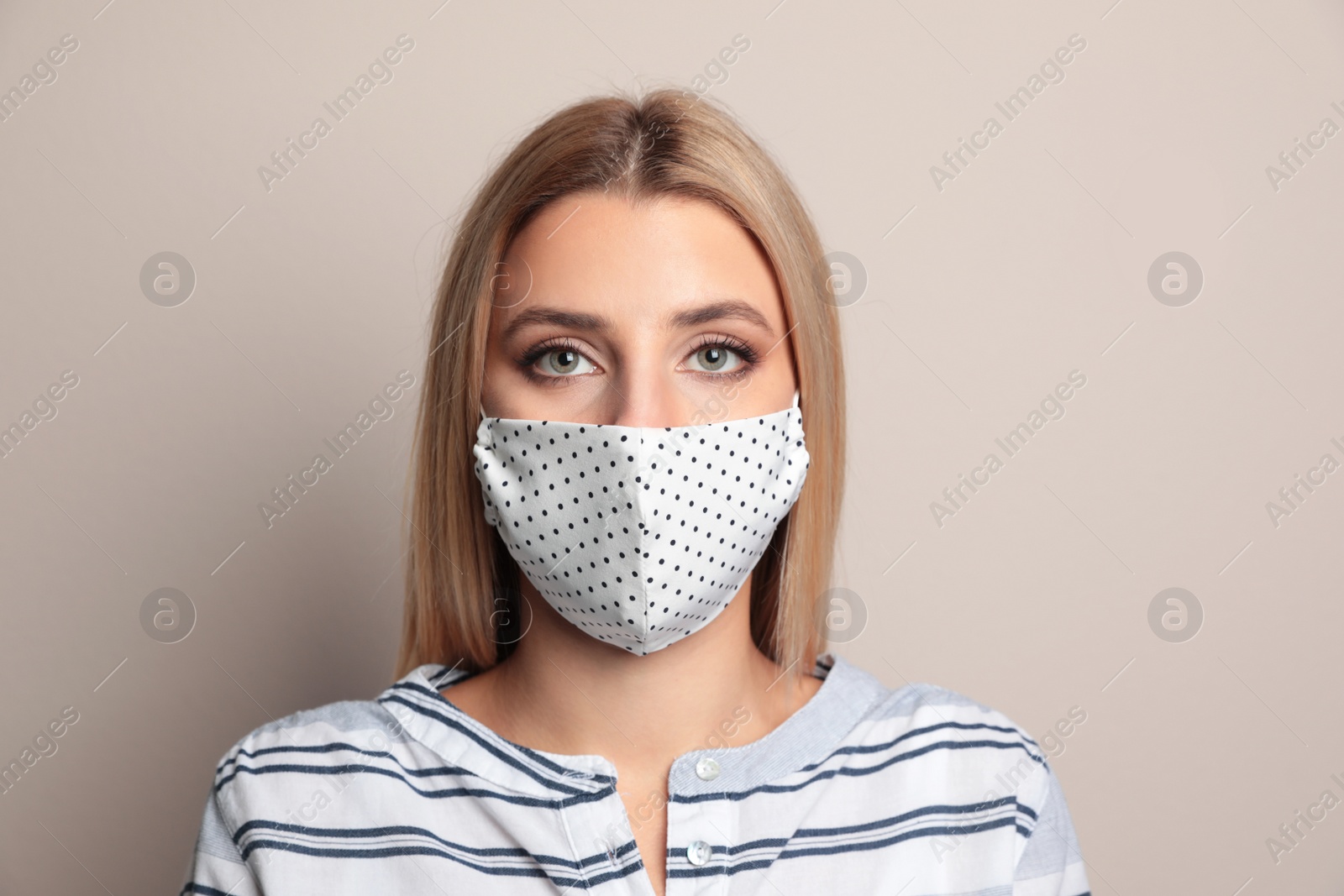 Photo of Young woman in protective face mask on beige background