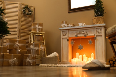 Photo of Fireplace with burning candles in festive room interior. Christmas celebration