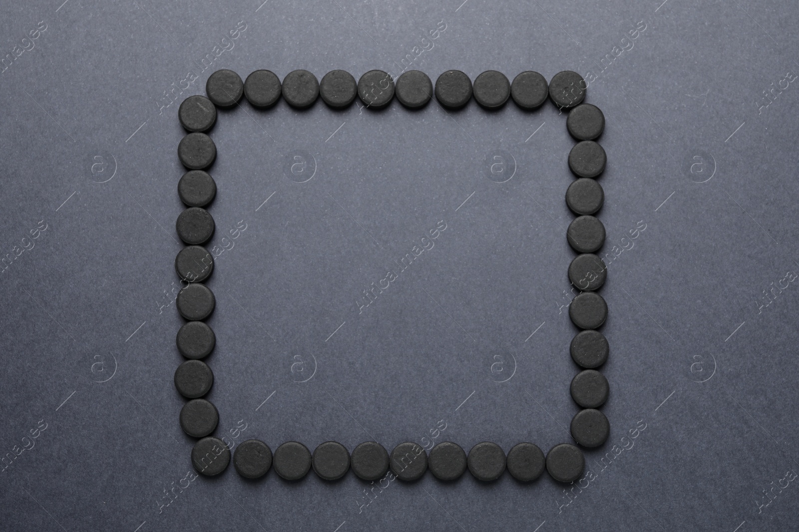Photo of Frame of activated charcoal pills on grey background, flat lay with space for text. Potent sorbent