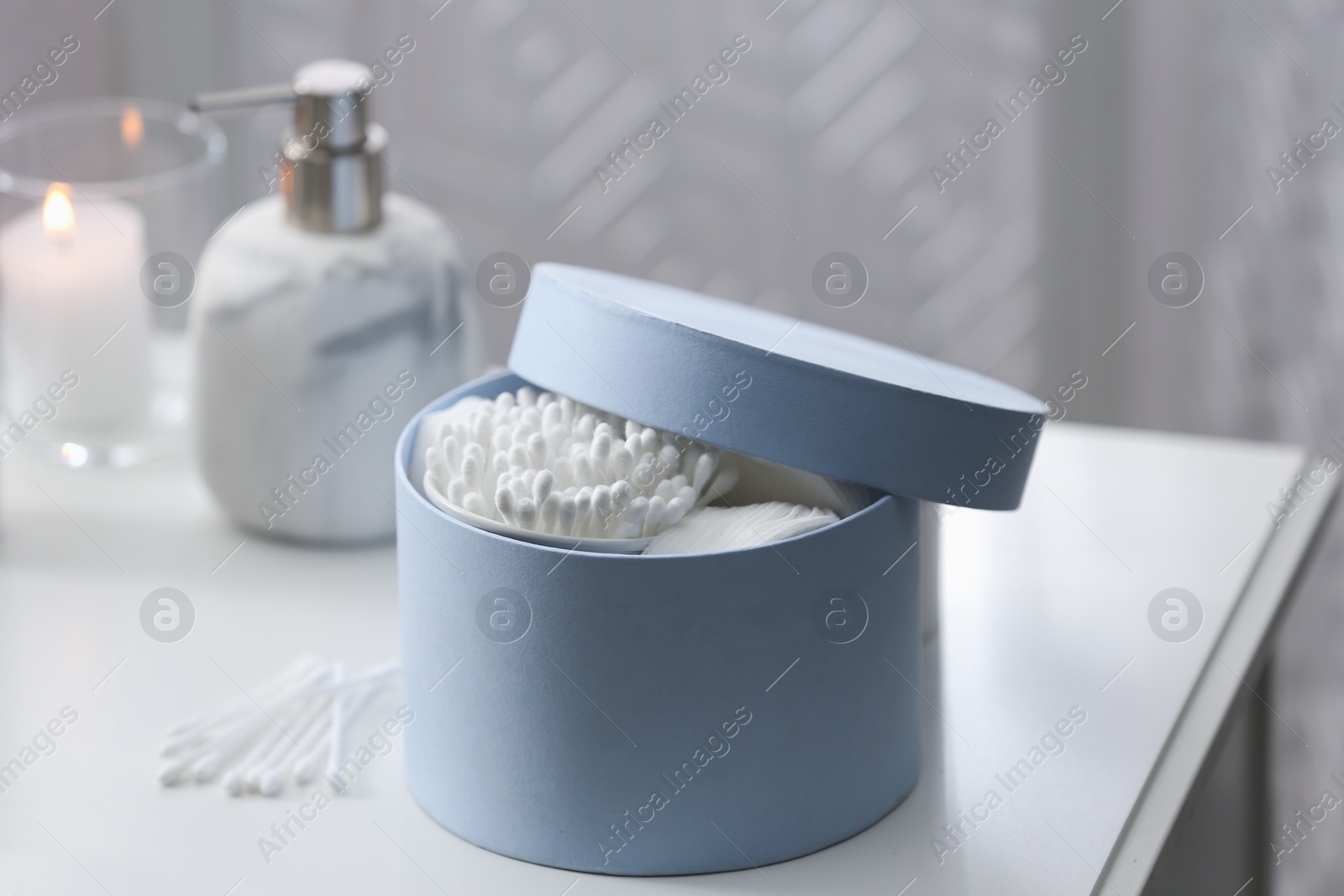 Photo of Cotton buds and pads in box on white table indoors