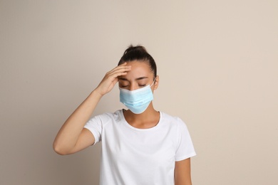 Photo of Stressed woman in protective mask on beige background. Mental health problems during COVID-19 pandemic